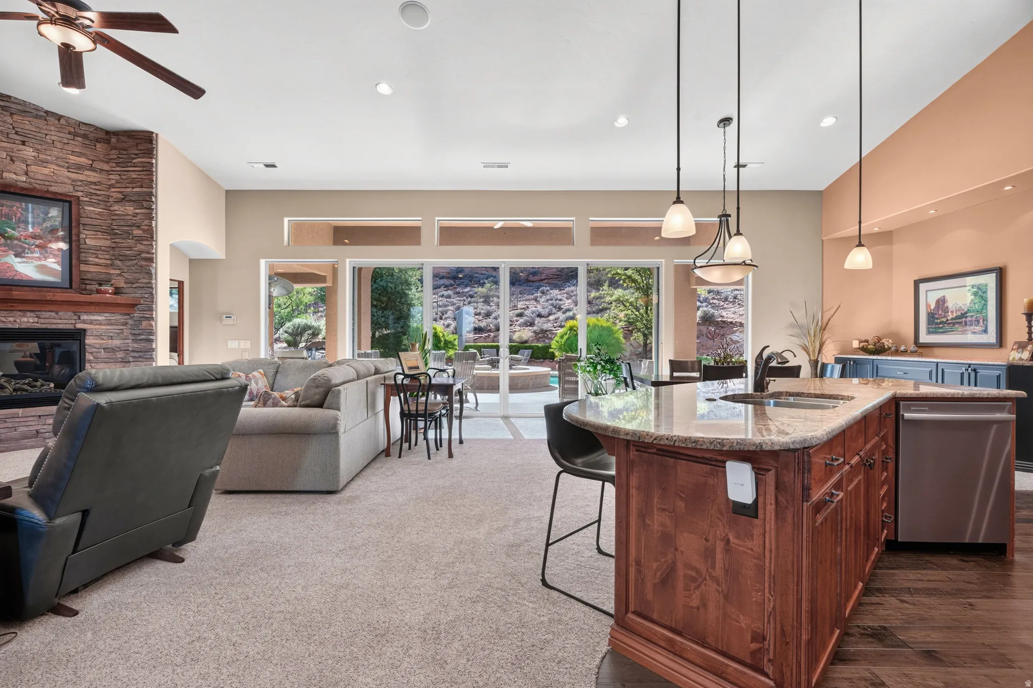 Spacious interior featuring a stone-clad fireplace, wood-finish ceiling fan, and large sliding glass doors