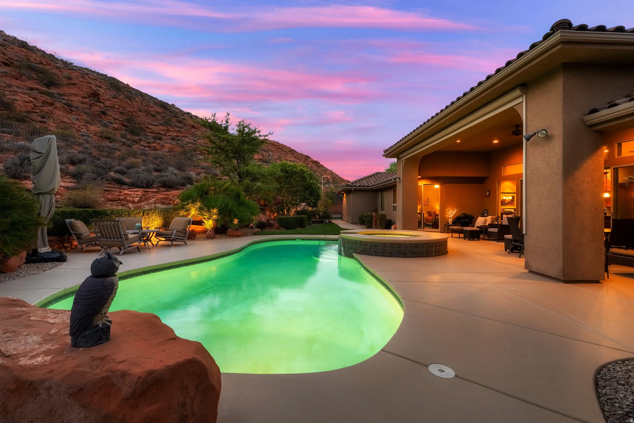 Curved swimming pool, integrated spa, expansive pool deck, covered patio, and desert landscaping