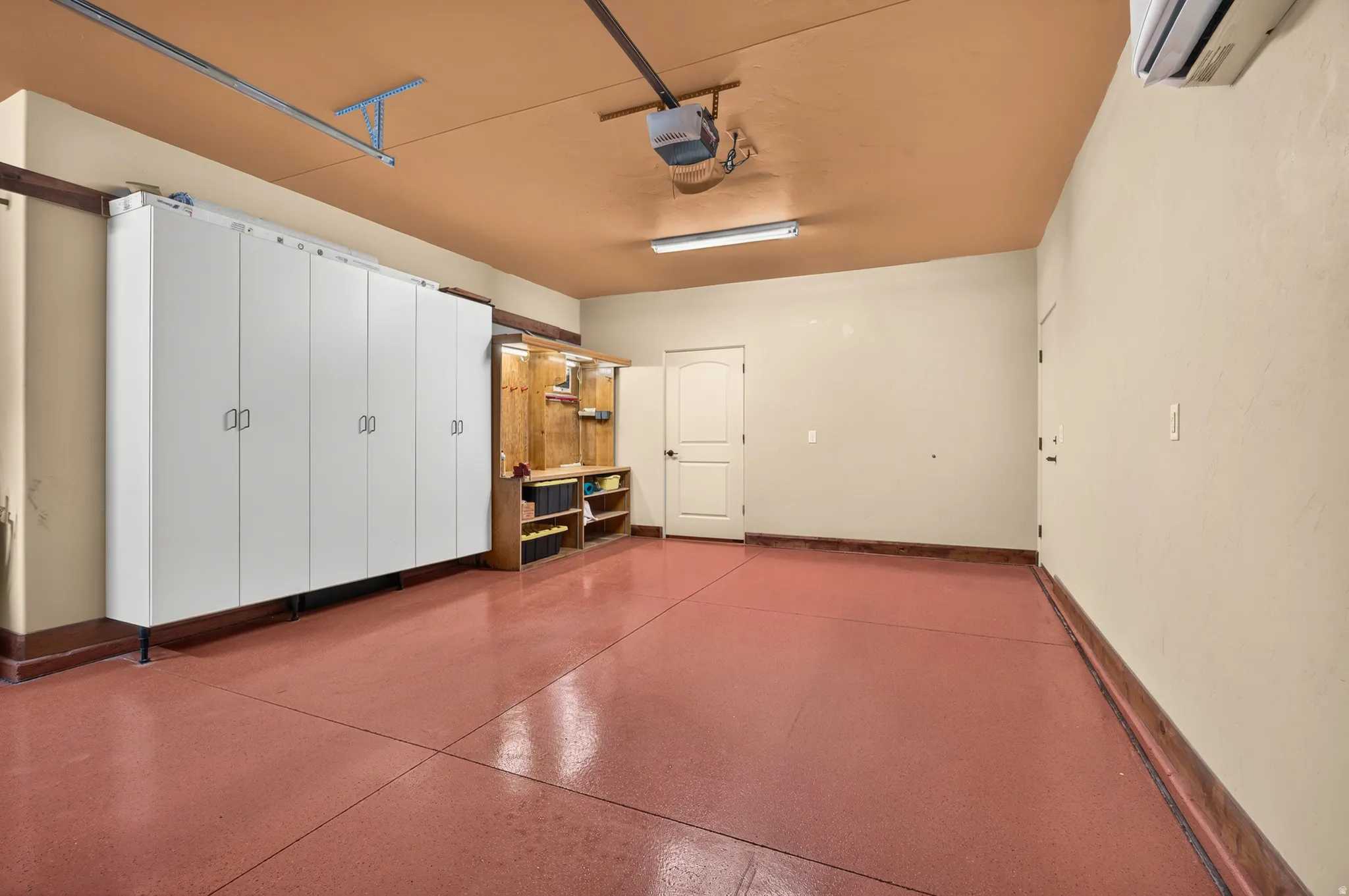 Expansive garage featuring a high-gloss floor finish, extensive built-in cabinetry, and integrated shelving with a workbench
