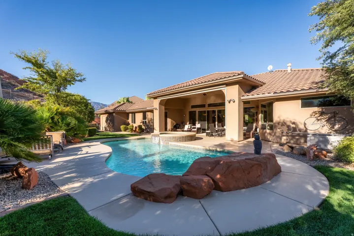 Outdoor swimming pool with integrated spa, expansive concrete patio, covered patio area, and desert landscaping