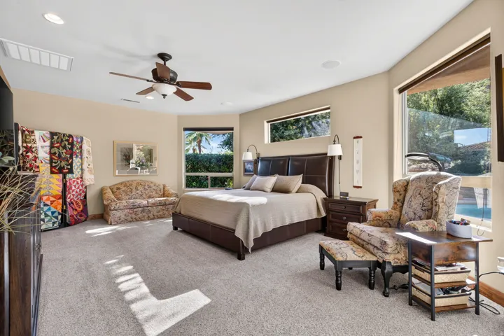 Spacious carpeted room featuring a ceiling fan, recessed lighting, and multiple windows