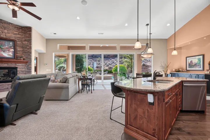 Spacious interior featuring a stone-clad fireplace, wood-finish ceiling fan, and large sliding glass doors