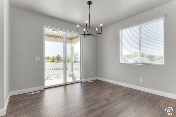 Wood-finish flooring, matte black multi-arm chandelier, sliding glass door, and window with horizontal blinds