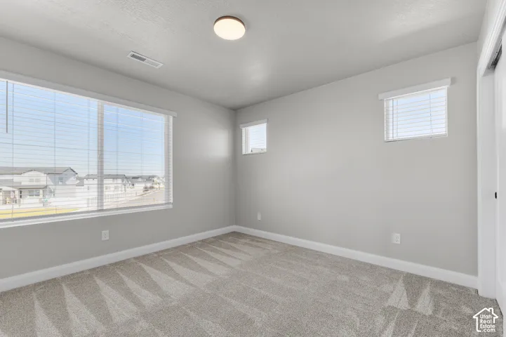 Neutral-toned interior featuring wall-to-wall carpeting, expansive windows with integrated blinds, and a flush-mount overhead light fixture
