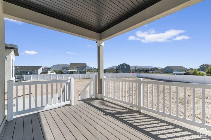 Covered patio featuring composite decking, white vinyl railings, and a dark-finished ceiling with mountain scenery