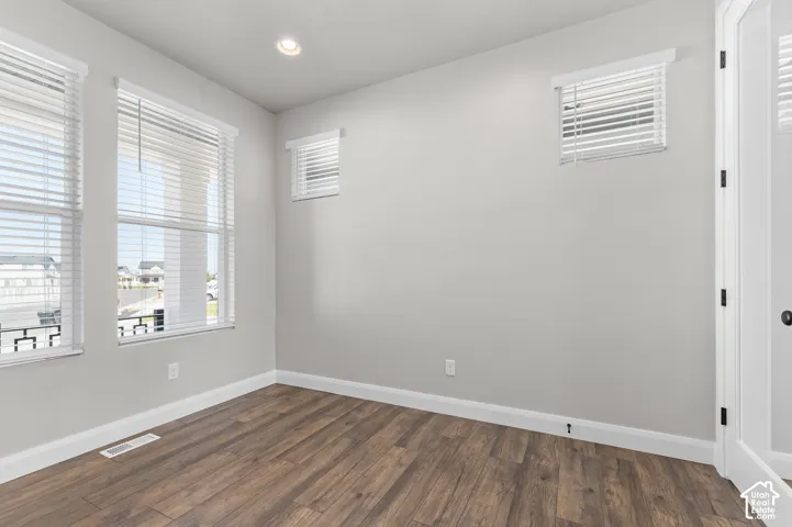 Room featuring wood-finish flooring, recessed lighting, neutral wall paint, and multiple windows with horizontal blinds