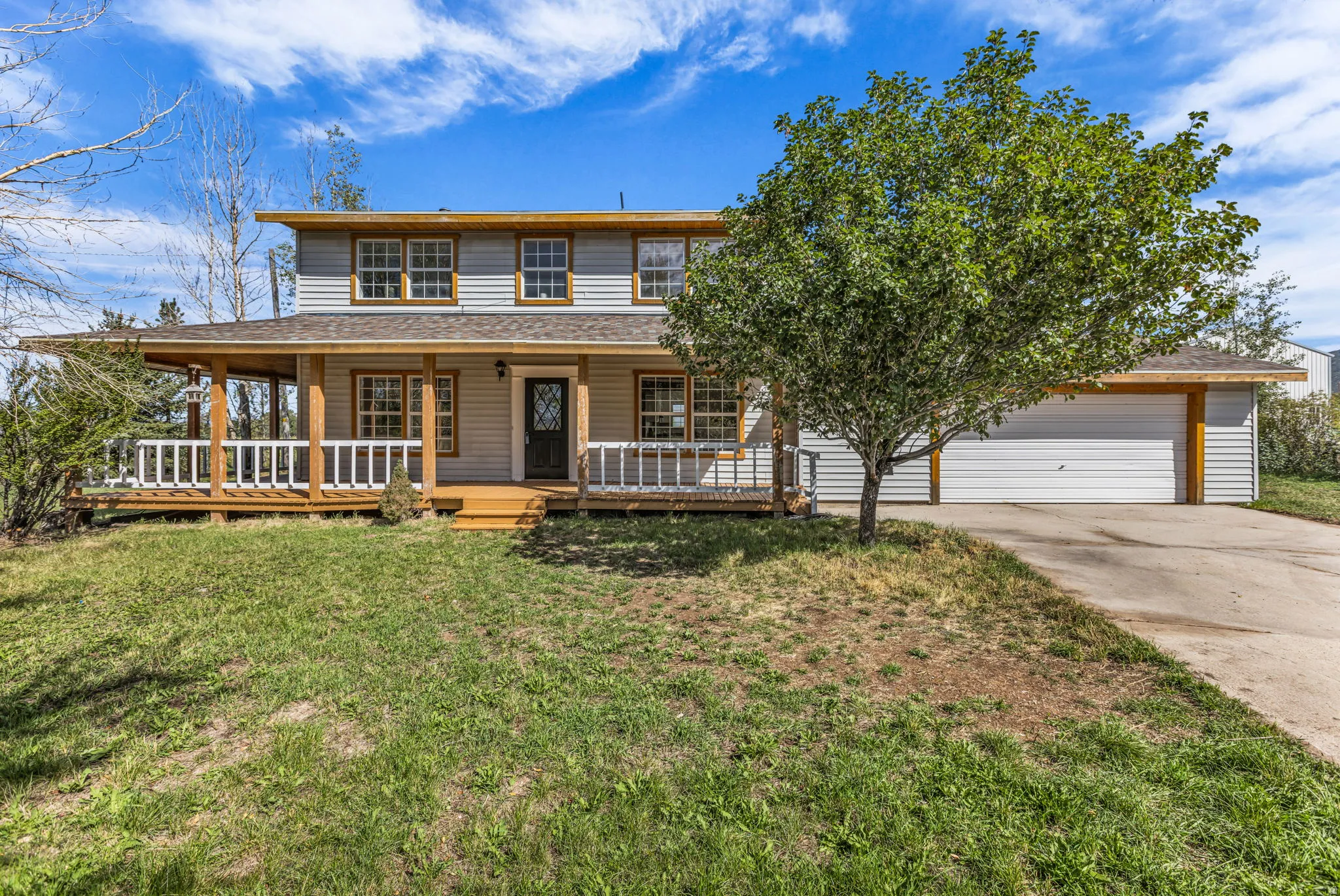 Two-story residence featuring light gray siding and a full-width covered porch with wood posts and white railings