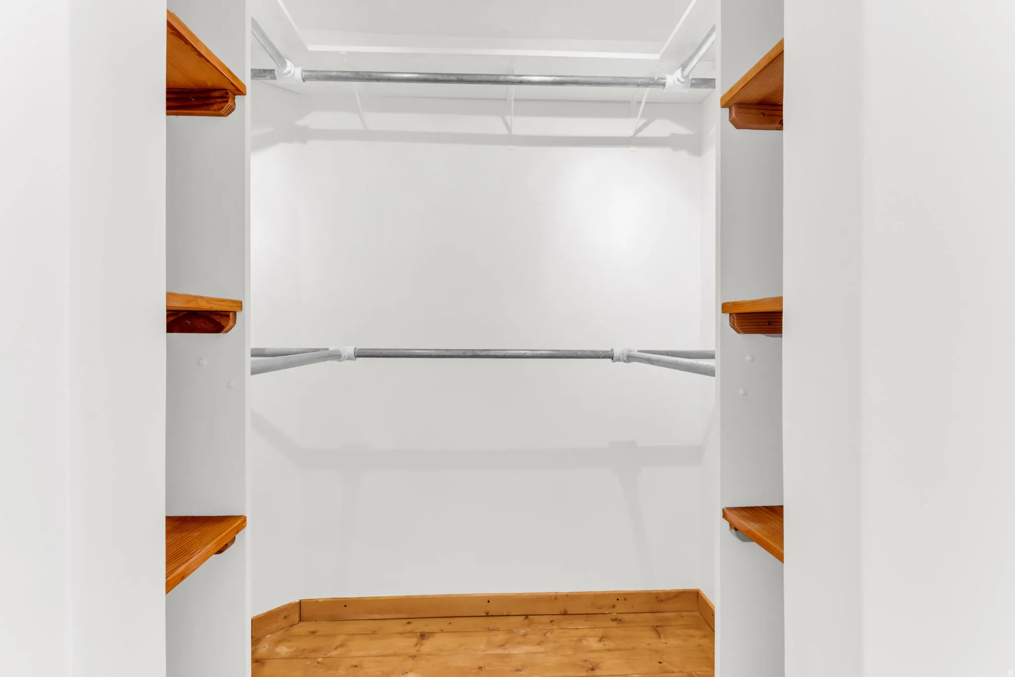 Built-in wood shelving with chrome hanging rods, showcasing wood flooring