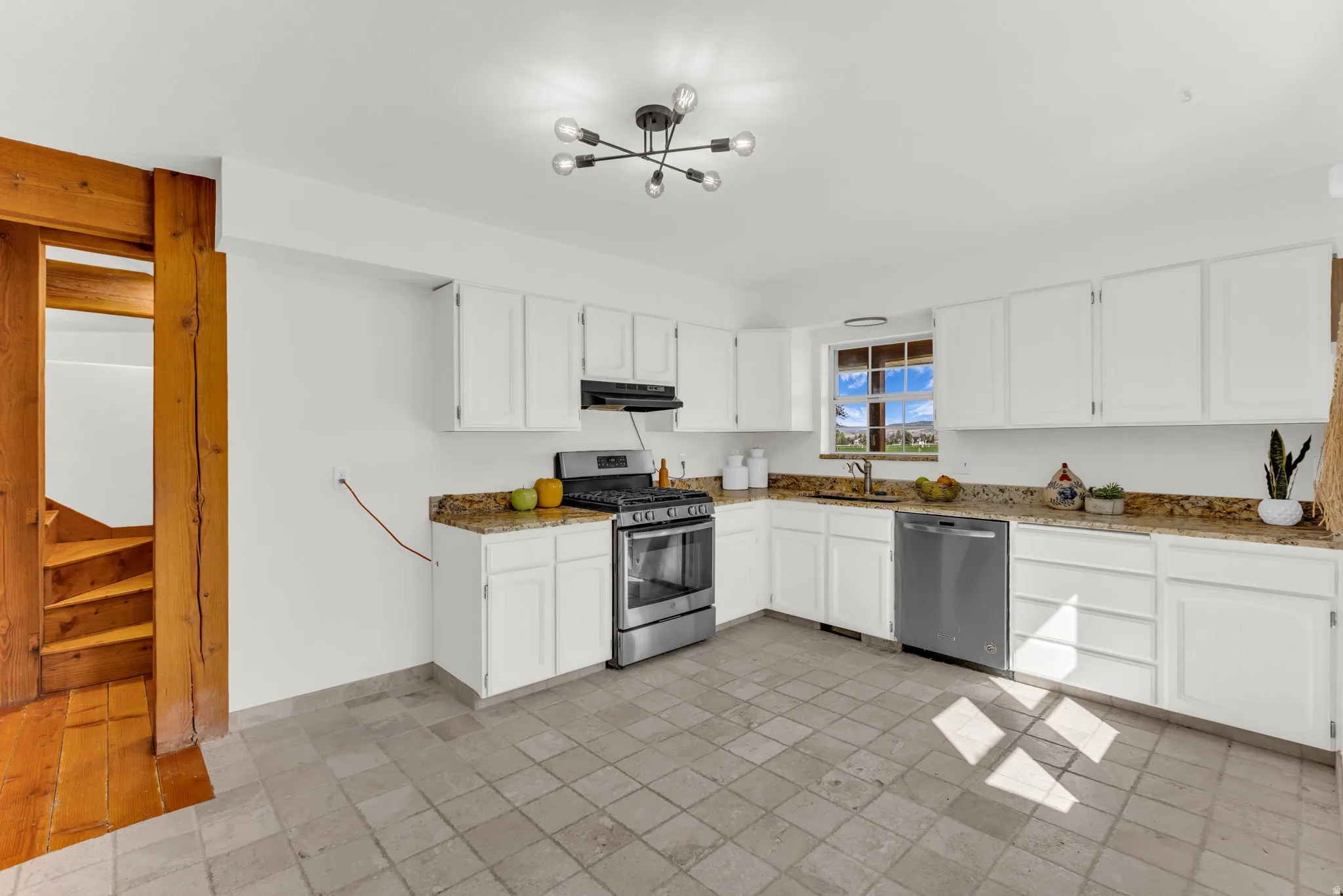 Kitchen featuring white cabinetry, stone-finish countertops, stainless steel appliances, and tile flooring