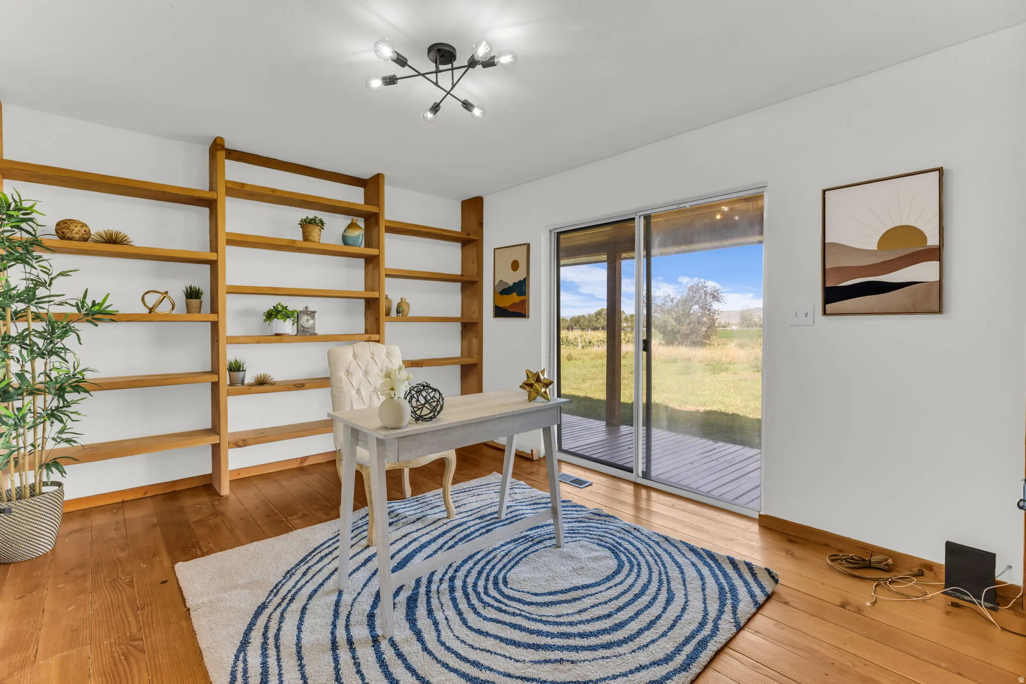Hardwood flooring with built-in wooden shelving, a sliding glass door, and a modern ceiling light fixture