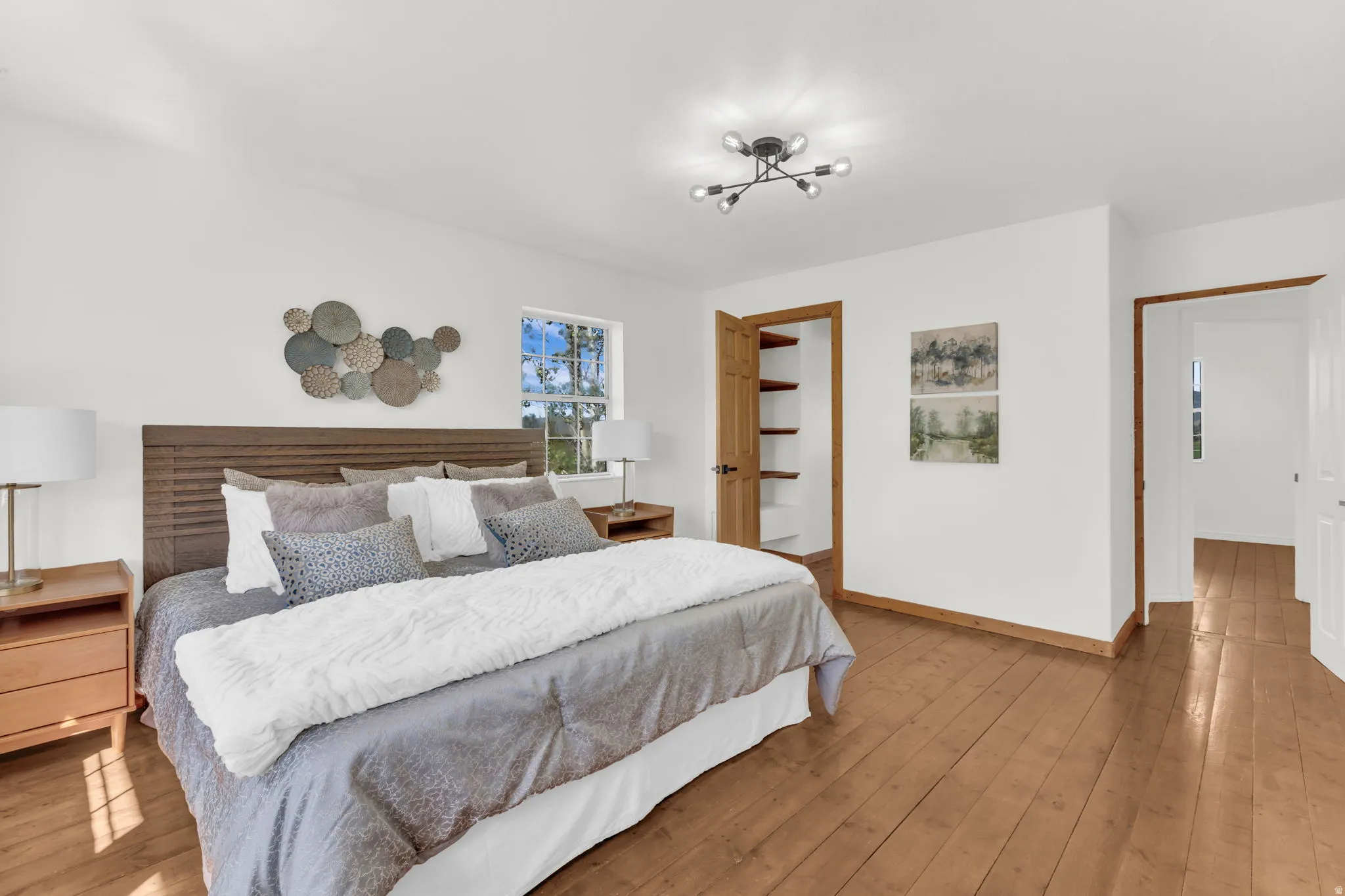 Primary Bedroom with hardwood flooring, recessed window, ceiling-mounted light fixture, built-in closet shelving, and wood trim accents