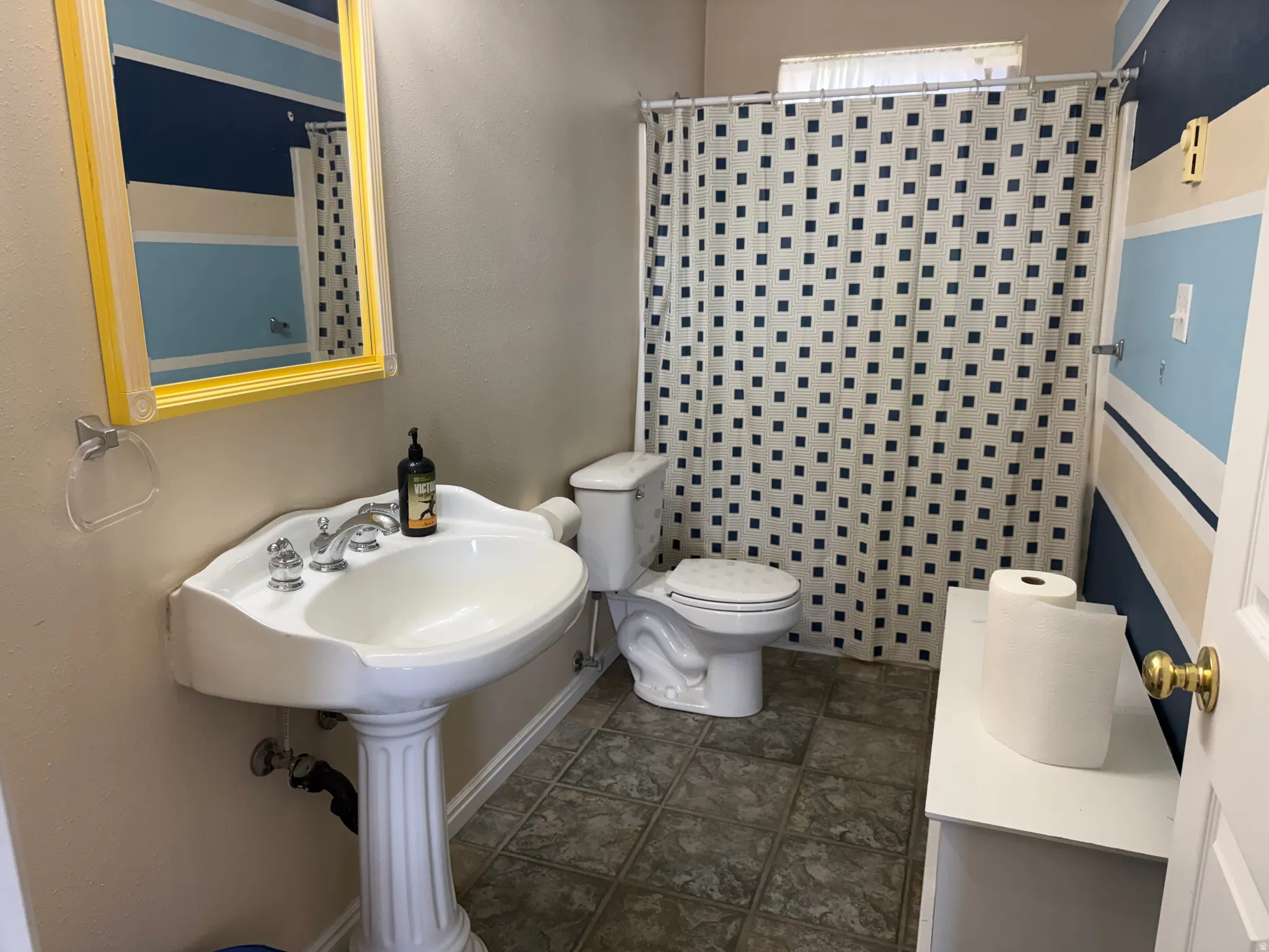 Pedestal sink with chrome fixtures and a framed mirror