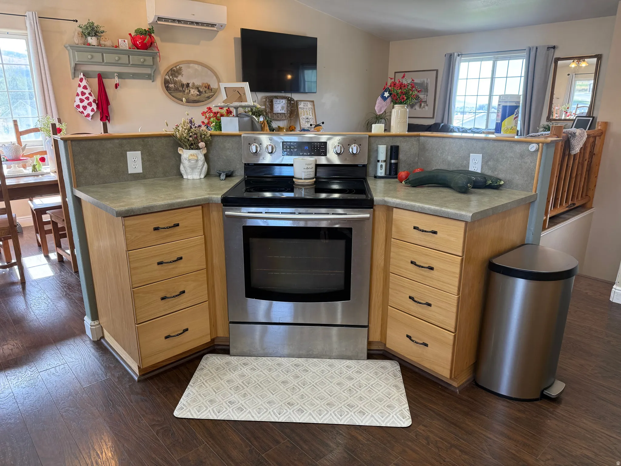Stainless steel range, wood-finish flooring, light wood cabinetry, stone-look countertops, and a built-in backsplash