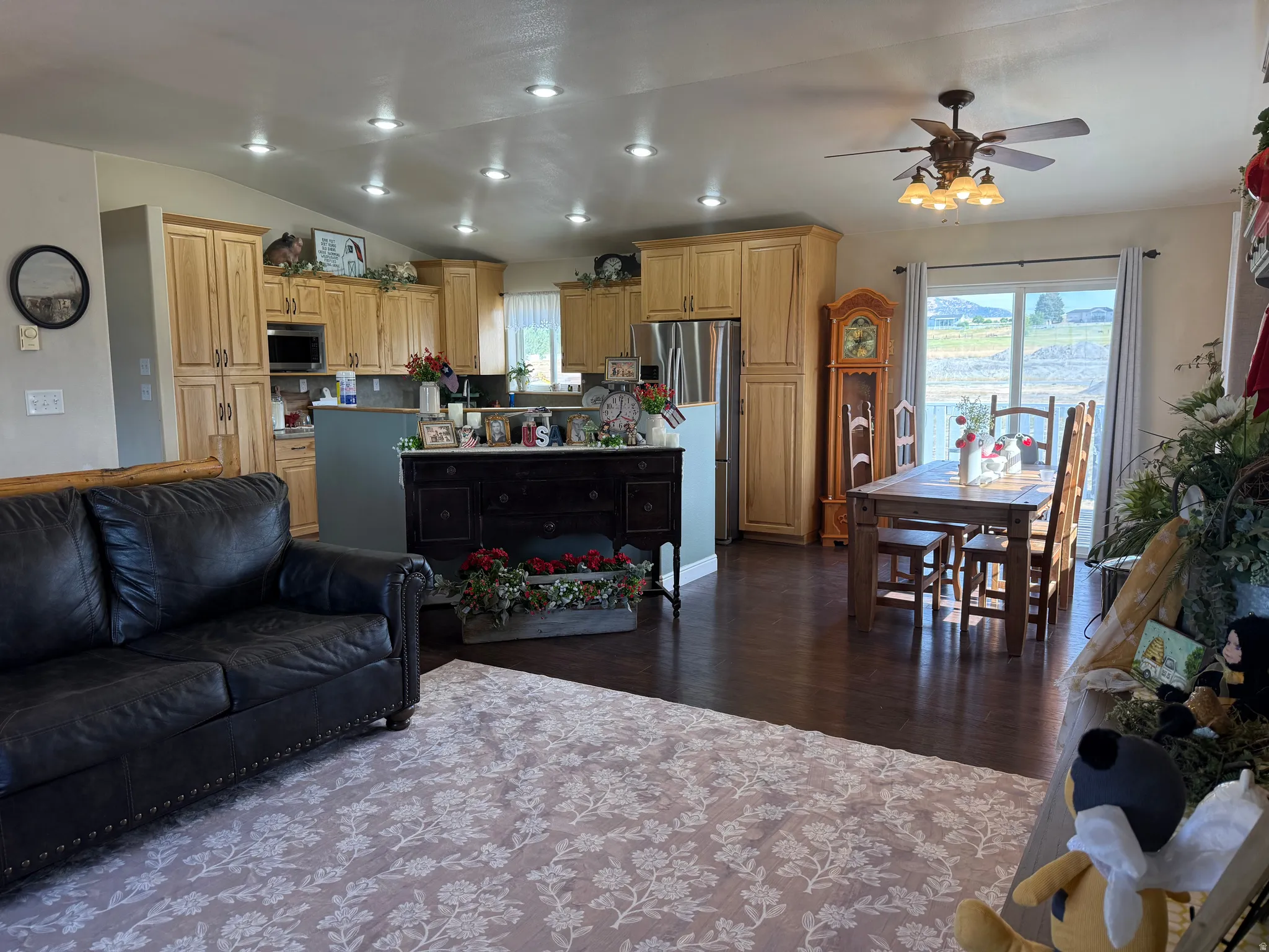 Expansive open-concept living area featuring recessed lighting, hardwood-finish flooring, a kitchen with light wood cabinetry, and a dining area with direct outdoor access