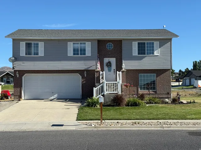 Brick and siding exterior with a two-car garage, white front porch railing, and established front yard landscaping