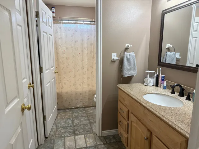 Bathroom featuring a wood-finish vanity with an integrated sink and a framed wall mirror