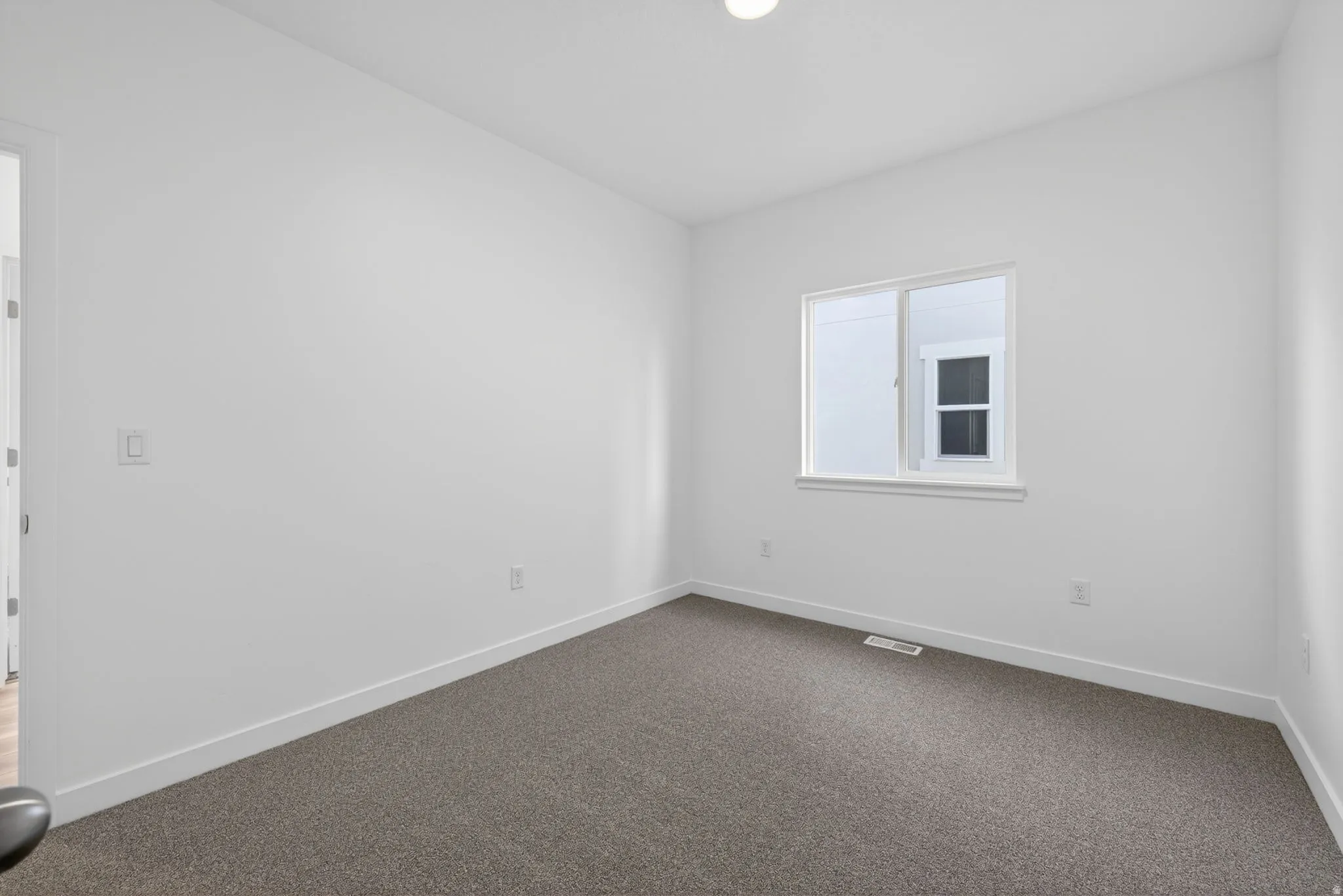 Neutral wall paint, plush carpet flooring, recessed lighting, and a white-framed window