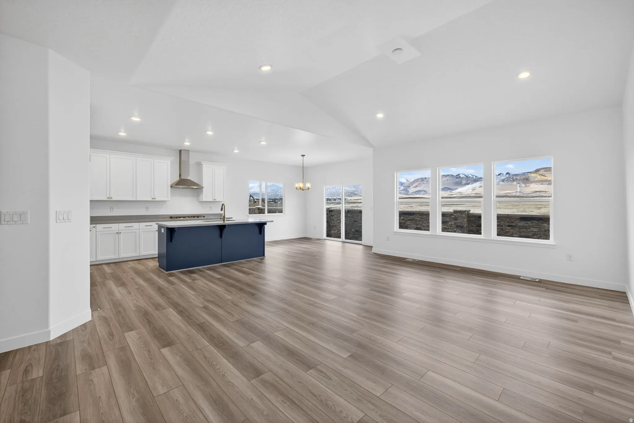 Open-concept living space with wood-finish flooring, vaulted ceilings, and recessed lighting