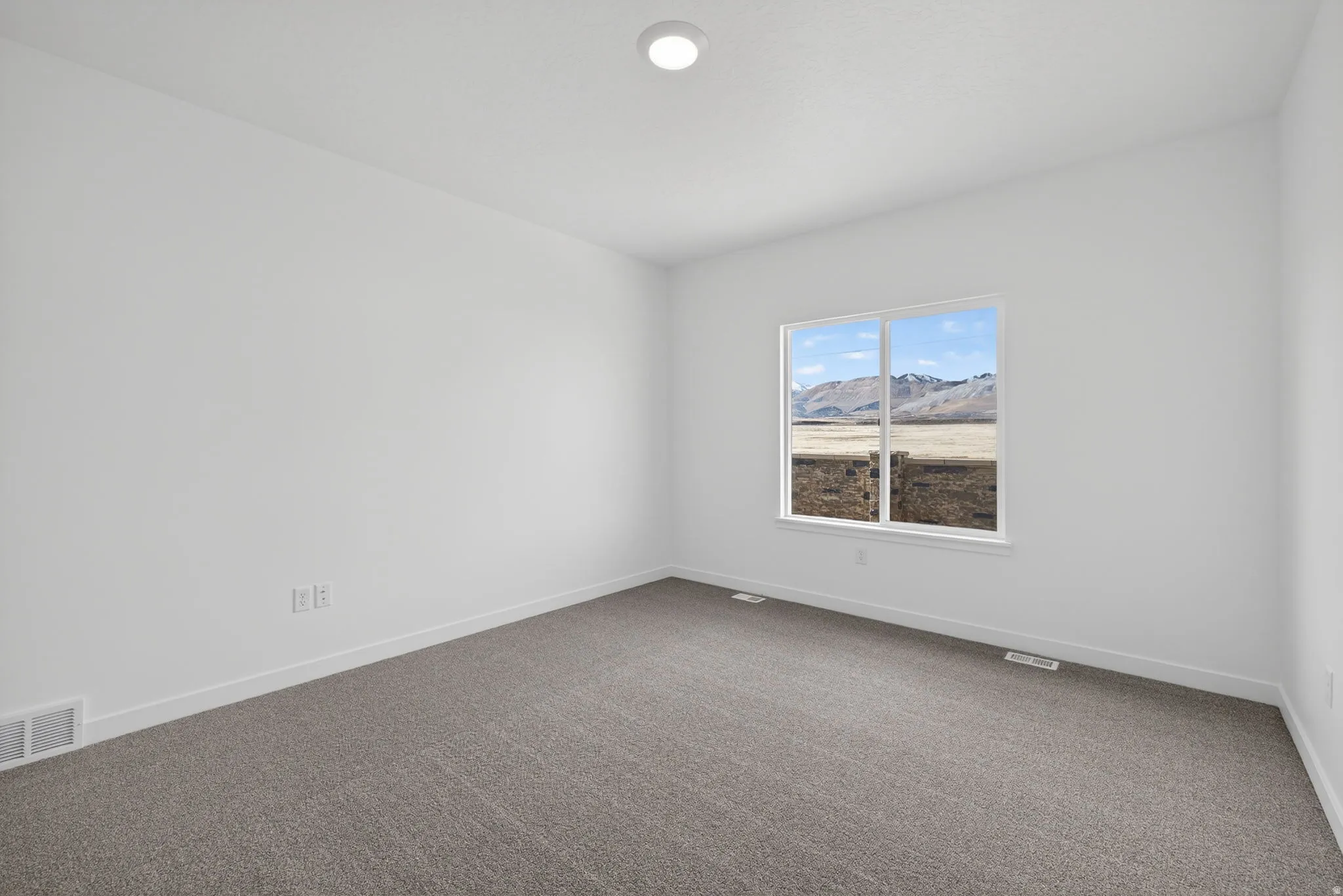 Recessed ceiling light, neutral wall color, gray carpeting, and a window with mountain scenery