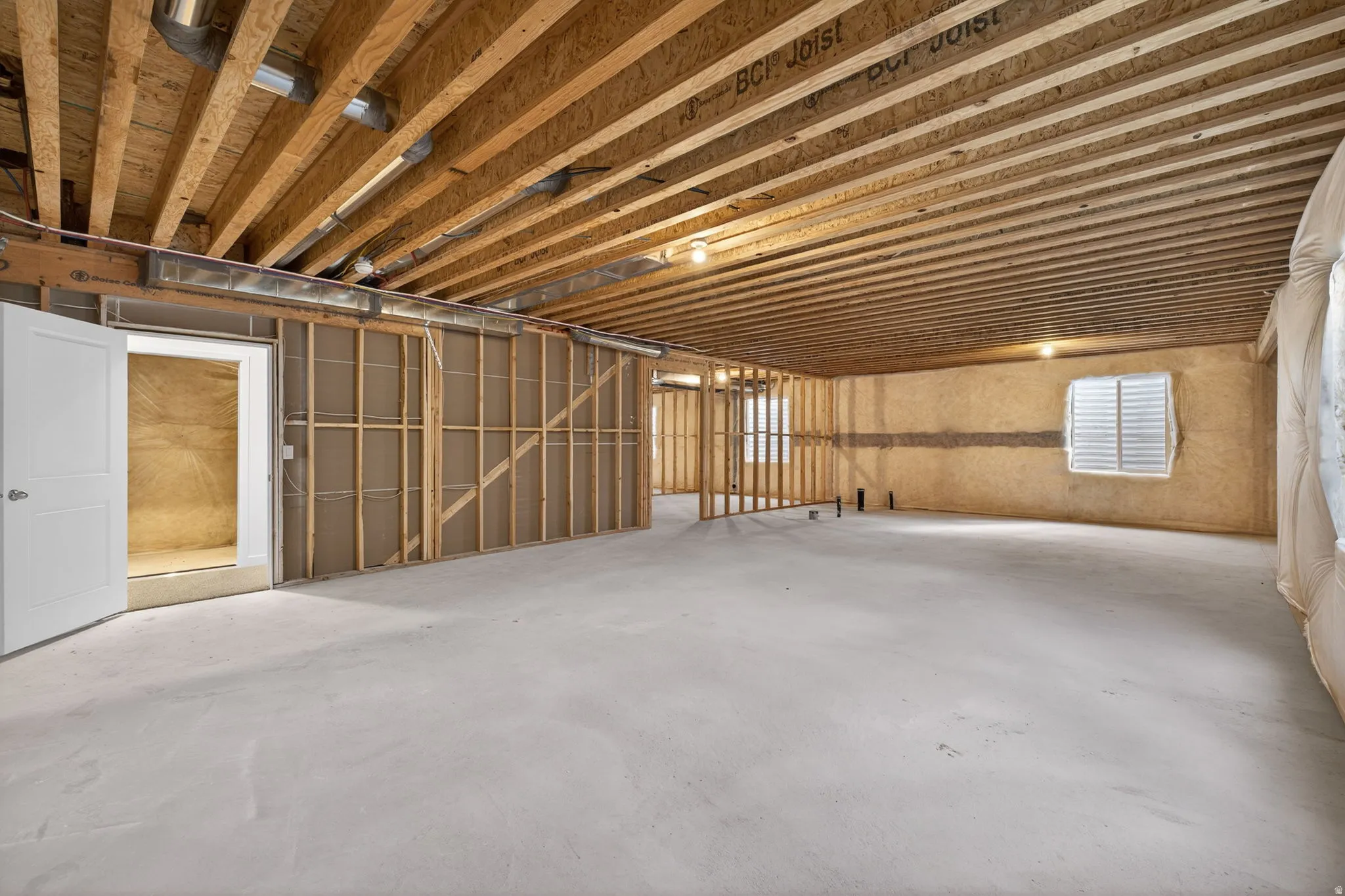 Unfinished basement featuring exposed wood joists, concrete flooring, and framed interior walls
