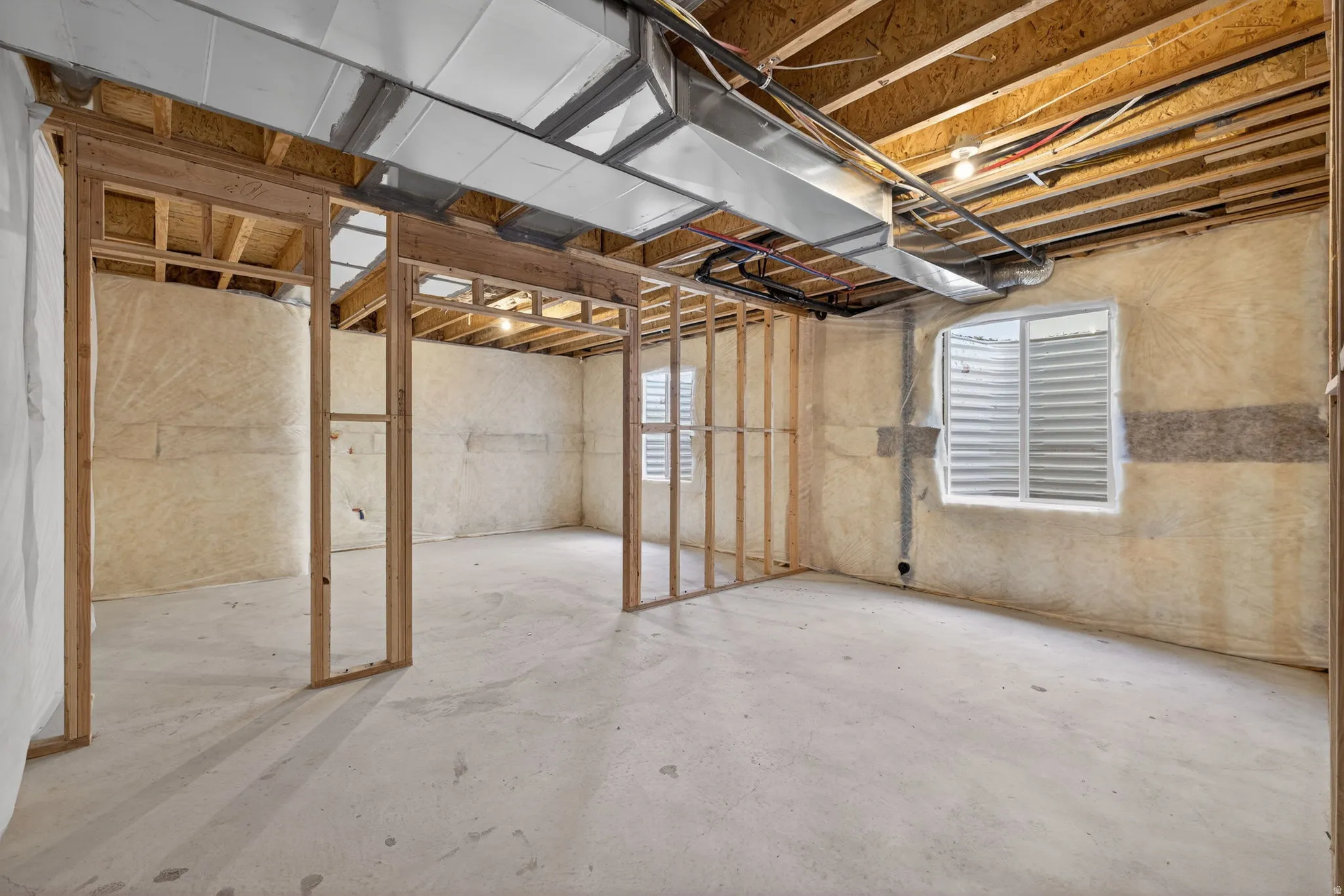 Unfinished basement with exposed ceiling joists and concrete flooring