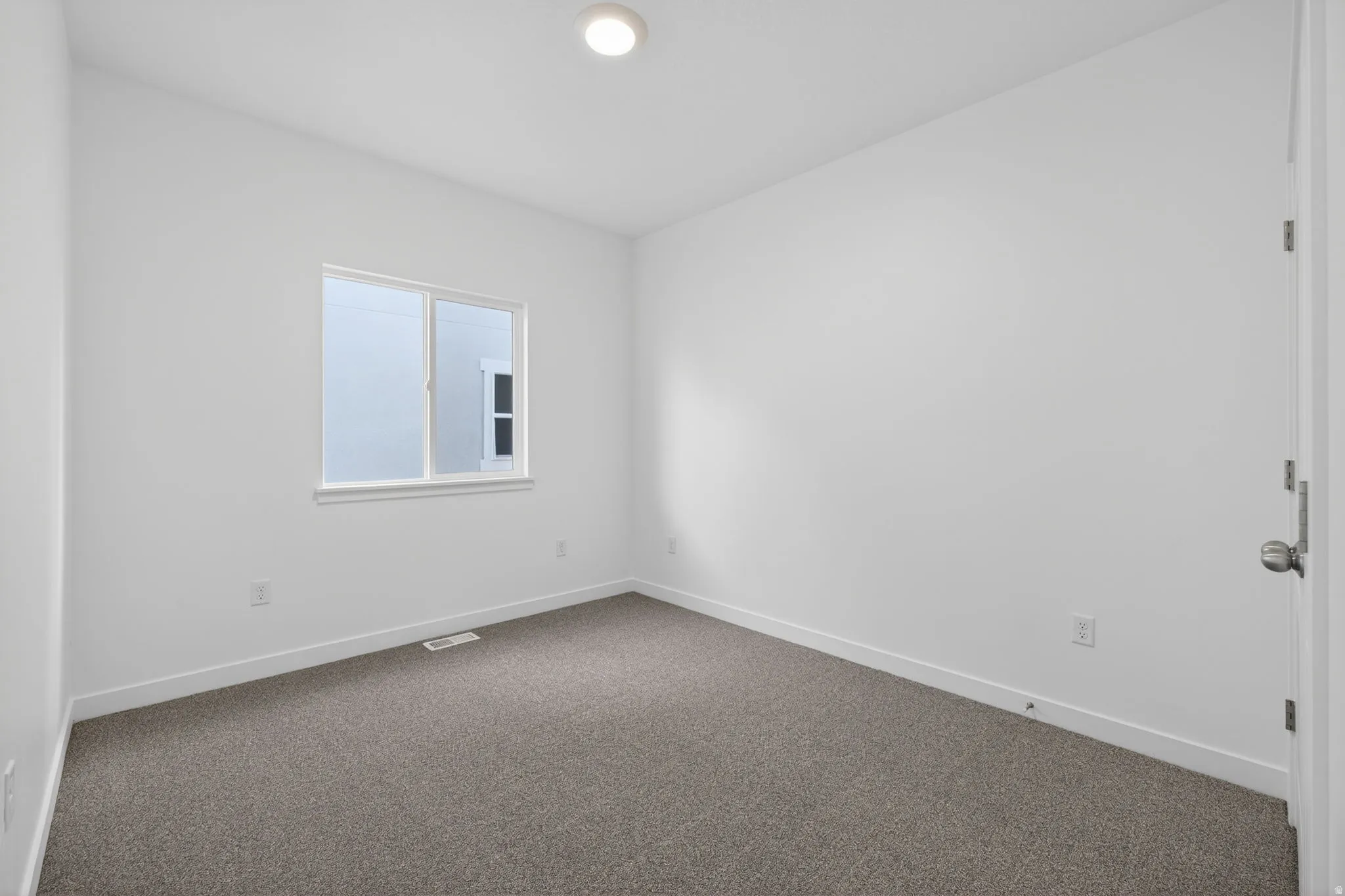 White painted walls, gray carpet flooring, flush mount ceiling light, white trim, and a single window