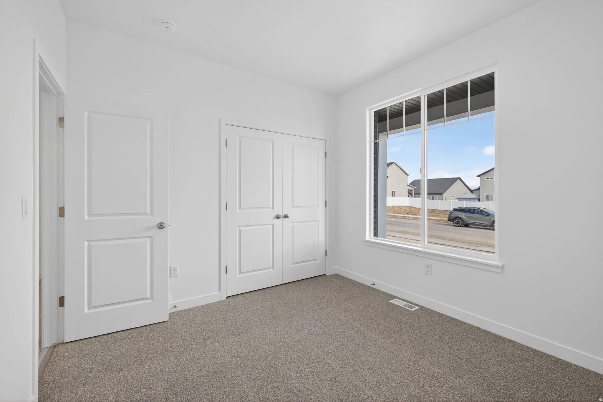 Light-filled room featuring a large window, carpeted flooring, and white walls