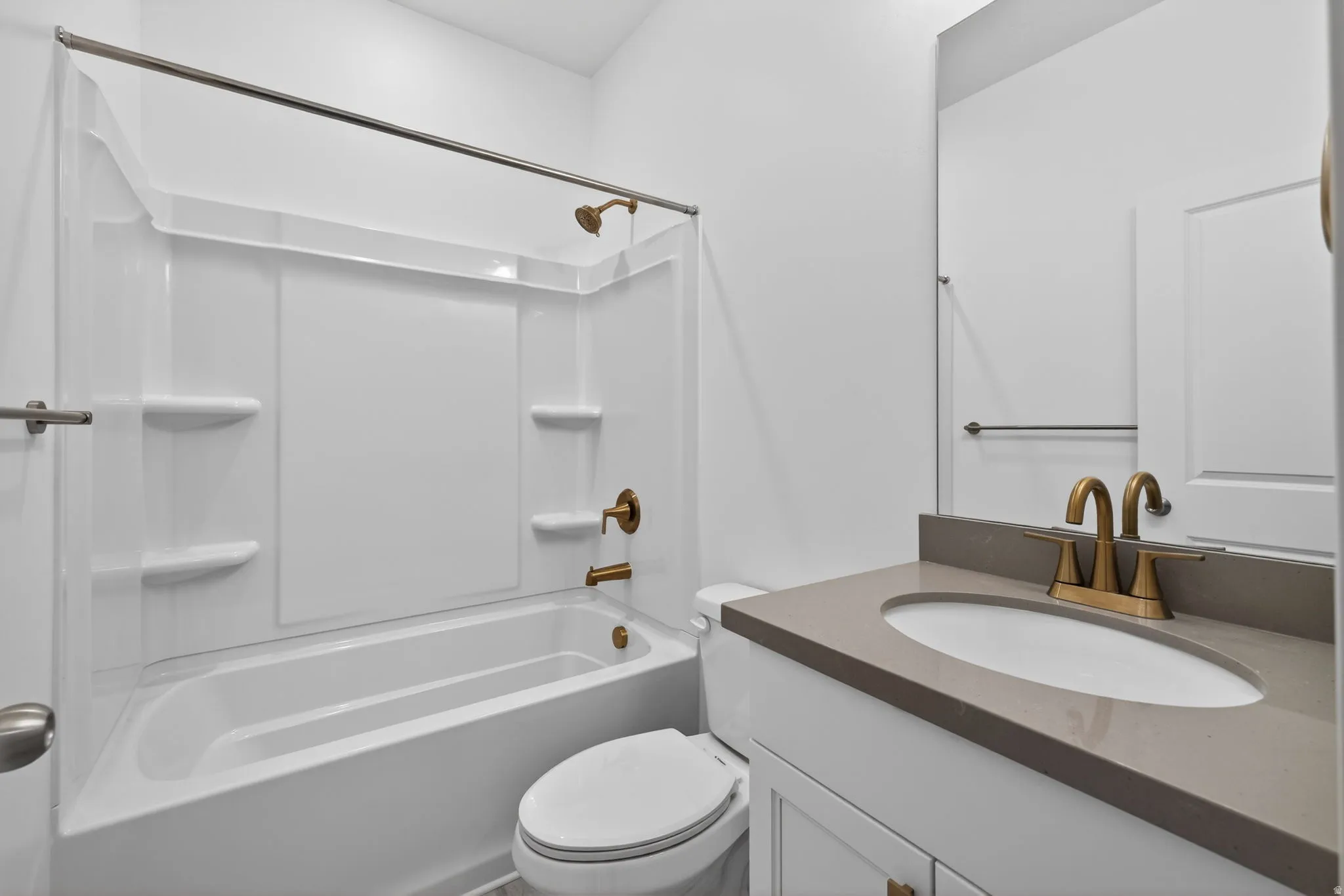 Bathroom featuring a white integrated tub and shower unit, bronze-finish fixtures, a vanity with a rectangular sink, and a gray countertop