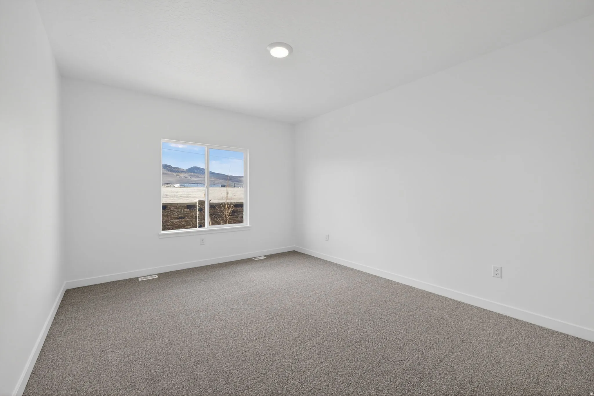 Recessed ceiling light, white walls, gray carpet, window with exterior scenery