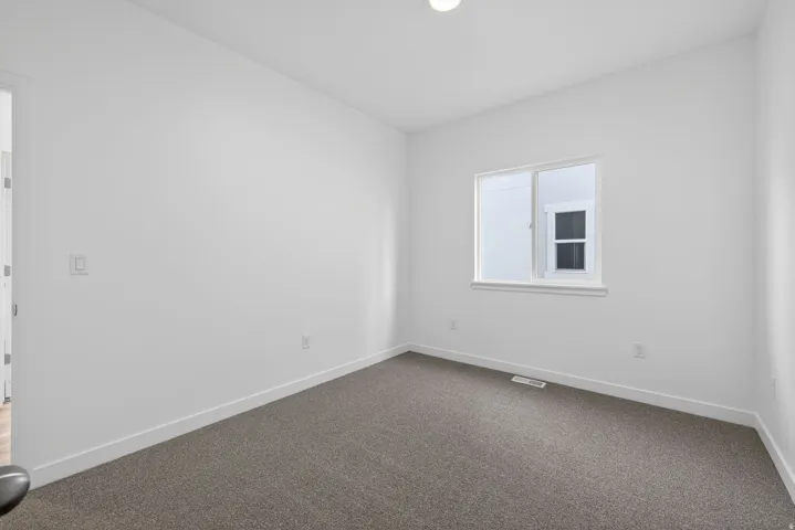 Neutral wall paint, plush carpet flooring, recessed lighting, and a white-framed window