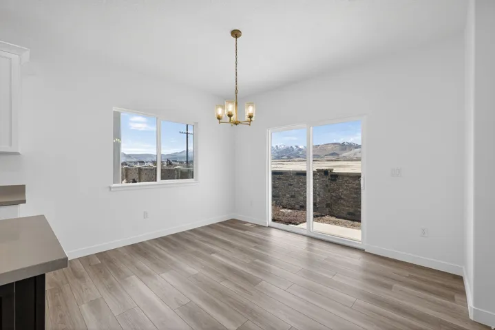 Light wood-finish flooring, white walls, and a brass-tone chandelier with glass shades