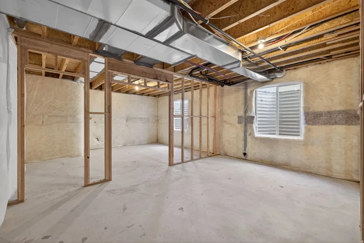 Unfinished basement with exposed ceiling joists and concrete flooring