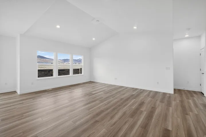 Wood-finish flooring throughout, vaulted ceiling, recessed lighting, and a triple-pane window array