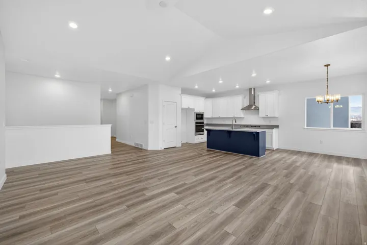 Open-concept living area featuring wood-finish flooring, recessed lighting, and a vaulted ceiling