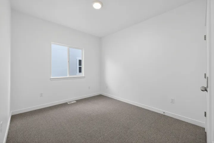 White painted walls, gray carpet flooring, flush mount ceiling light, white trim, and a single window