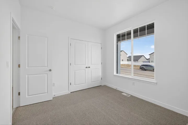 Light-filled room featuring a large window, carpeted flooring, and white walls
