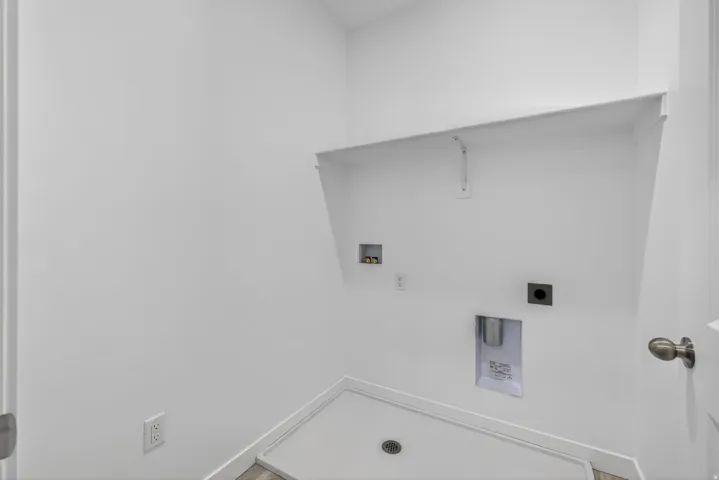 Dedicated utility space featuring a built-in shelf, appliance hookups, and a floor drain