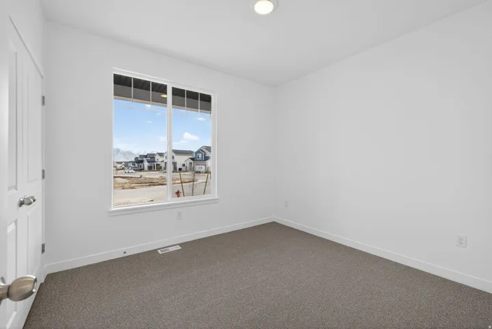 Recessed ceiling light, white painted walls, large window, gray carpeting, and white trim