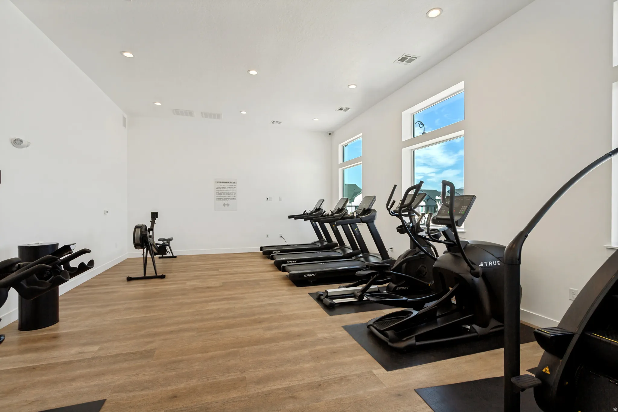 Fitness center featuring multiple exercise machines, wood-finish flooring, white walls, and recessed lighting