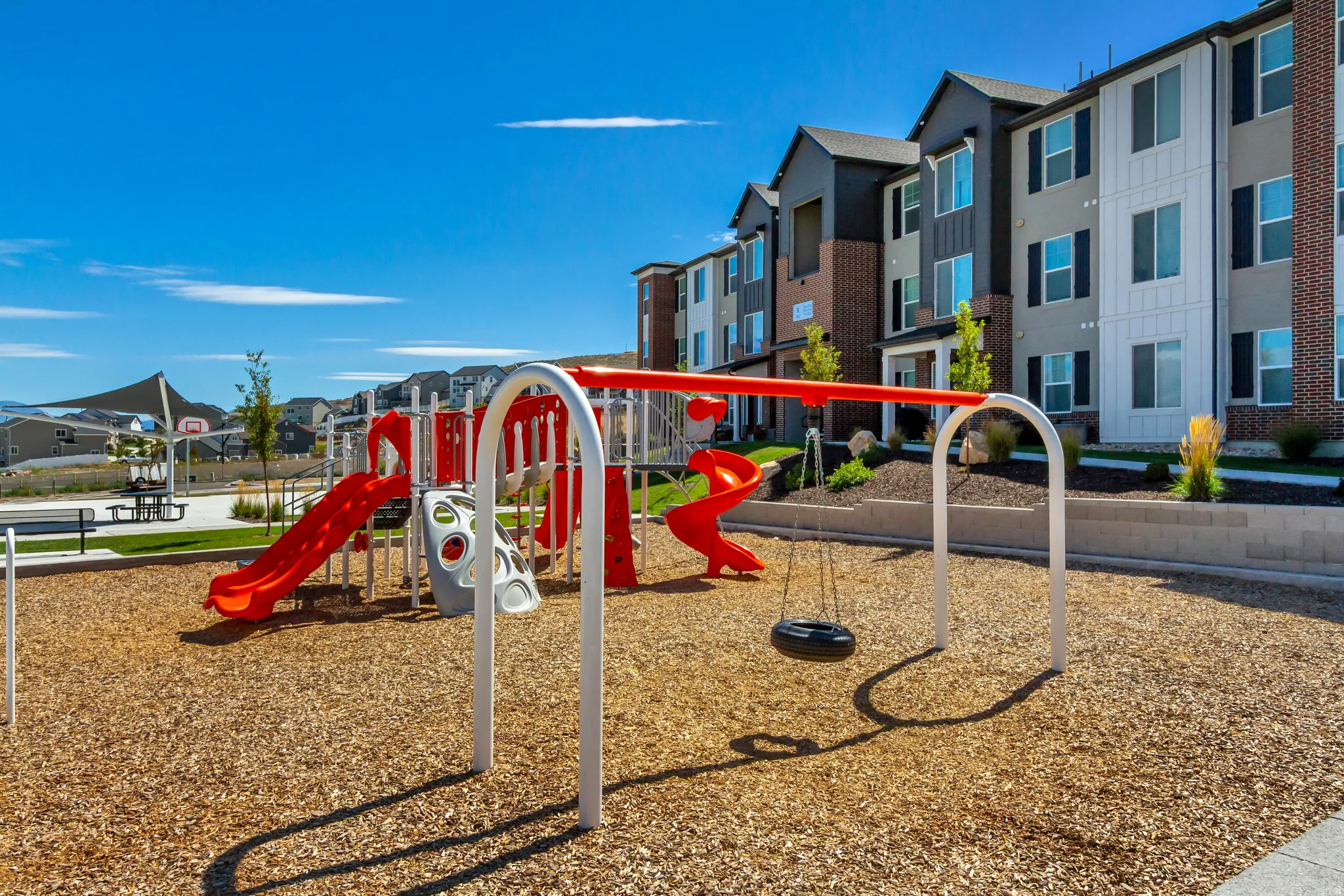 Community playground with wood chip surfacing, red slides, and swing set