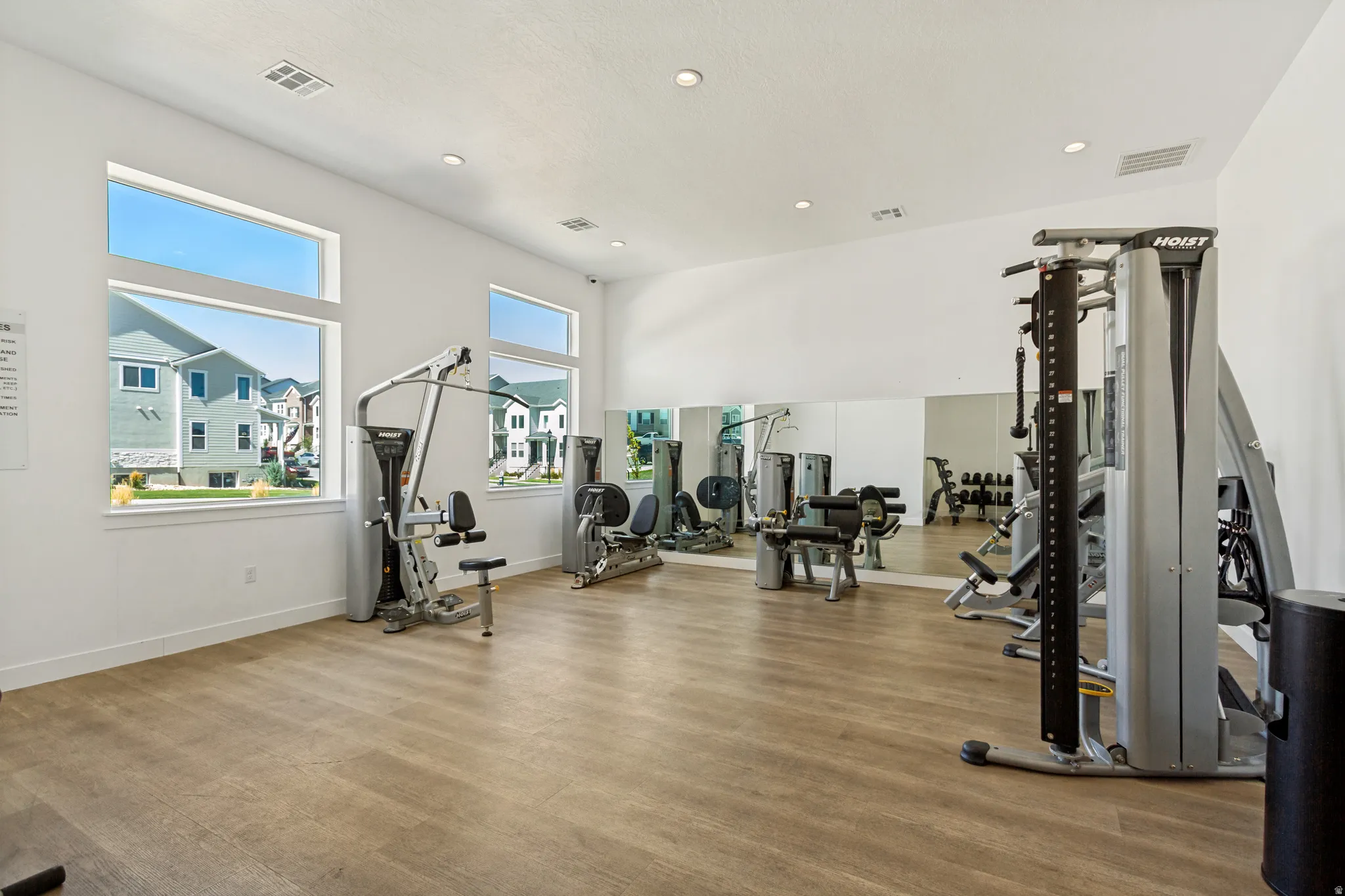Fitness center featuring wood-finish flooring, recessed lighting, and mirrored walls