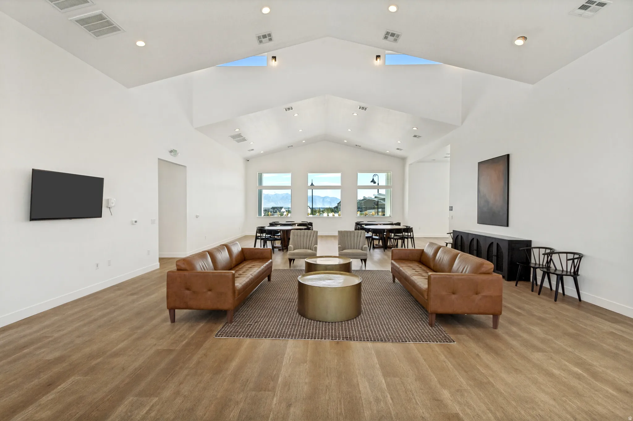 Vaulted ceiling with recessed lighting and skylights, wood-finish flooring, and multiple windows