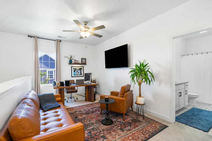 Loft space featuring a ceiling fan, window with roller shade, and built-in shelving