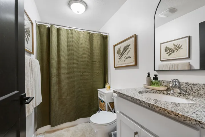 White vanity with chrome hardware, speckled countertop, and integrated sink