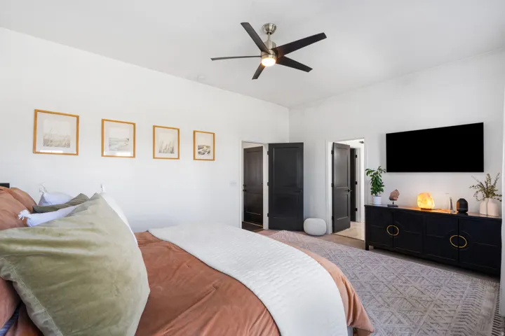 Vaulted ceilings, contemporary ceiling fan with brushed nickel accents, dark panel doors, wall-mounted display, and light-toned flooring