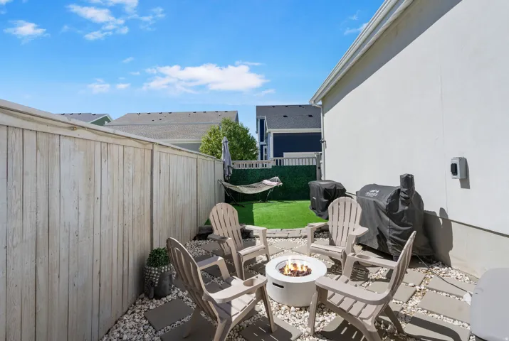 Private patio with paver stones and decorative rock, artificial turf area, and wood fencing