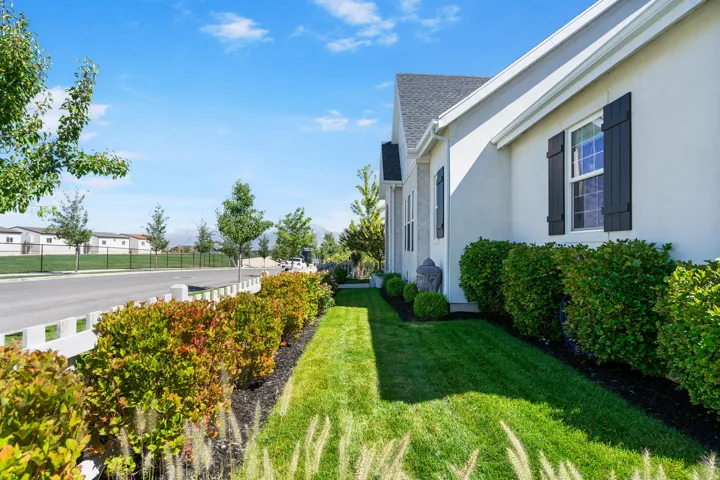 Well-maintained exterior featuring stucco siding, dark window shutters, and a sloped roof