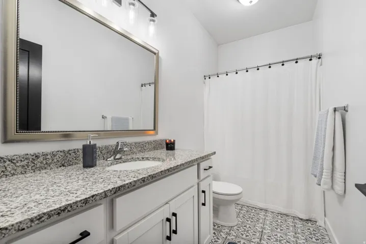 Vanity with a light-colored speckled countertop, undermount sink, and white cabinetry