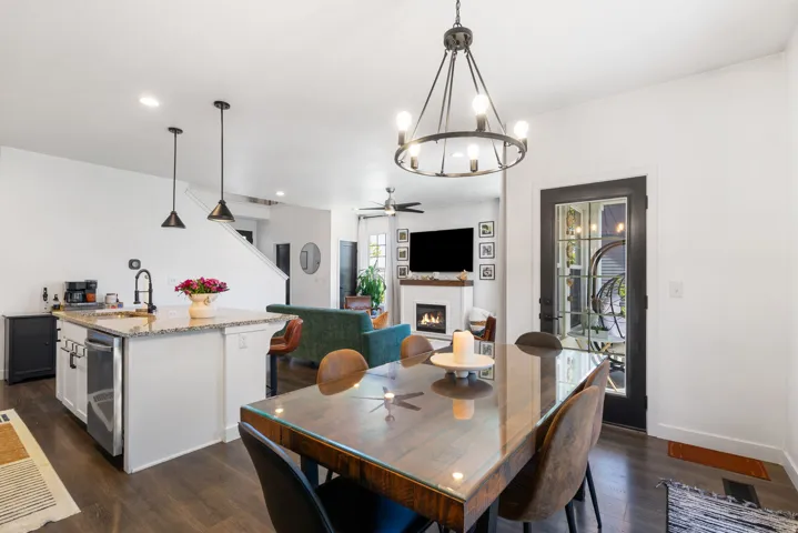 Open concept living area with dark wood-finish flooring, a kitchen island with granite countertops, and a dining area with a chandelier