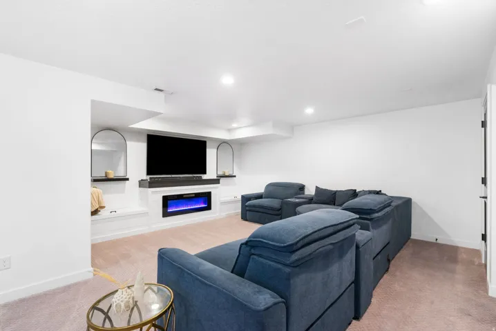 Integrated media wall with an electric fireplace, built-in shelving, and recessed lighting